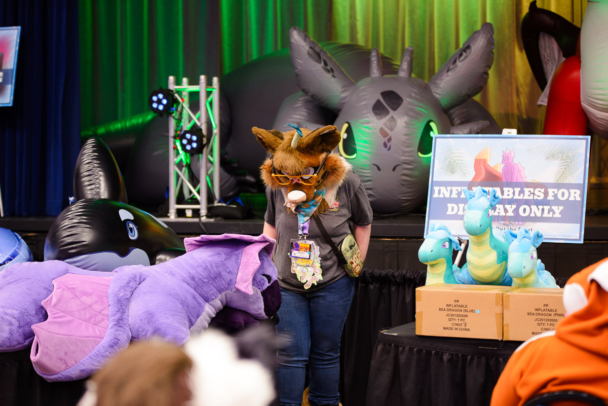 One of the Charity fursuit volunteers next to some of the raffle prizes from 2025