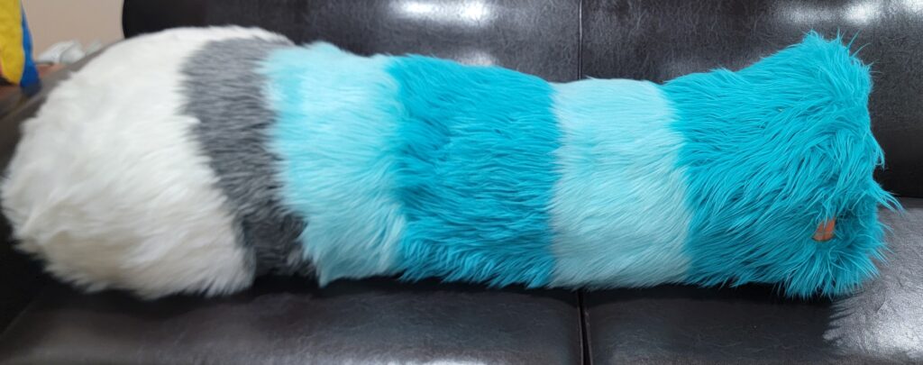 A four foot long floor dragger fursuit tail, in multiple shades of blue, white, and grey.