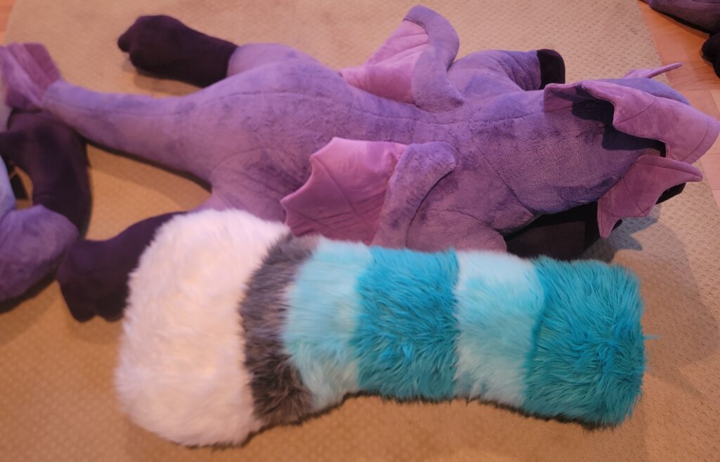 The four foot long floor dragger fursuit tail next to Finneus plush for scale. It is almost as plushy around the middle as Finneus is.